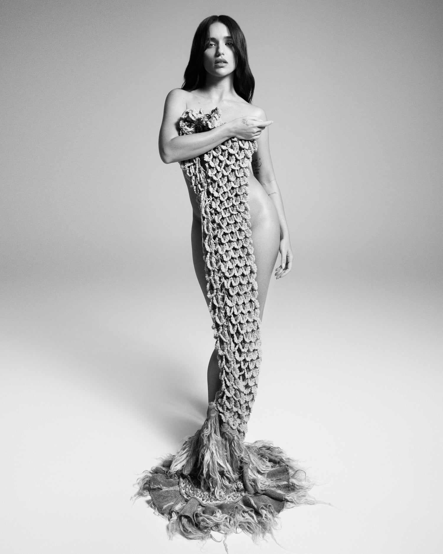 Black and white editorial shot of Rafa Kalimann in floor length signature ACIEN coronation crochet textile. Bottom of the textile features fur details.