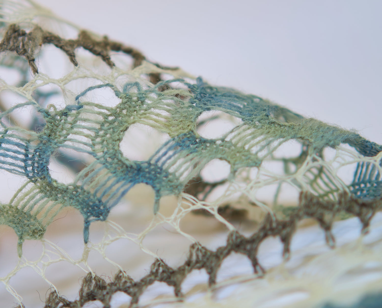 Close-up of blue, green, white and brown knit textile for REWILDING TEXTILES, dyed with bacterial dyes with algae and food waste dyes.